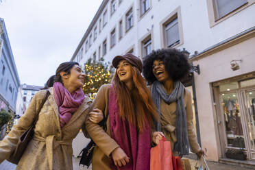 Glückliche gemischtrassige Freunde gehen mit Einkaufstaschen in der Stadt spazieren - JCCMF08713