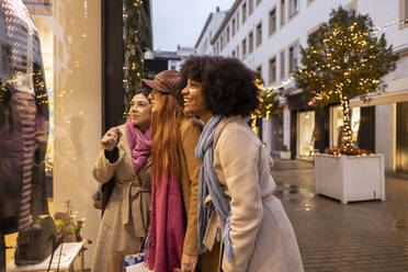 Happy young friends enjoying window shopping together in front of store - JCCMF08717