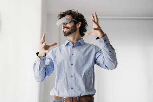 Engineer wearing VR glasses gesturing in office - EBBF07597