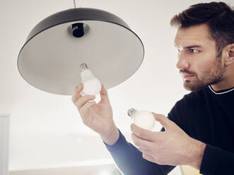 Man changing old lightbulb for a LED energy saving lightbulb - PWF00395