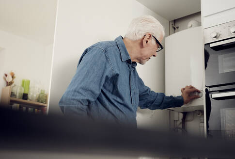 Älterer Mann stellt Heizkessel zum Energiesparen zu Hause ein - PWF00405