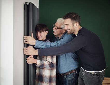 Son, father and grandfather at home touching and hugging radiator - PWF00419