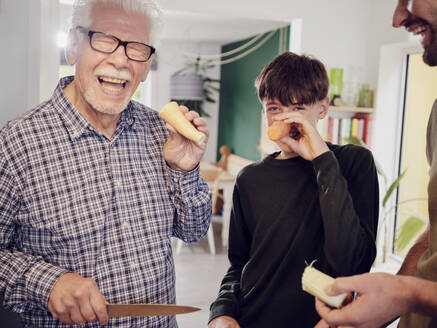 Großvater und Enkel in der Küche und haben Spaß mit Karotten - PWF00460