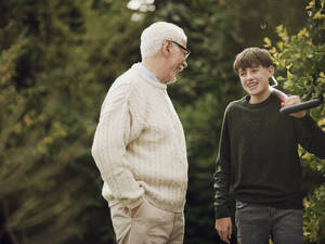 Großvater und Enkel unterhalten sich im Garten Junge trägt Gartengabel - PWF00476