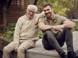 Adult son sitting with father in garden - PWF00489