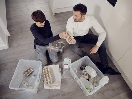 Father and son separating waste into recycling boxes - PWF00517