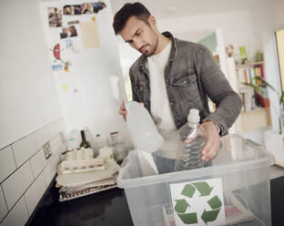 Mann legt getrennten Abfall in die Recyclingbox - PWF00534