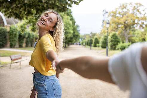 Glückliche junge Frau hält Hand von Freunden im Park - WPEF06872
