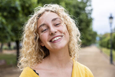 Happy young woman with blond hair in park - WPEF06877