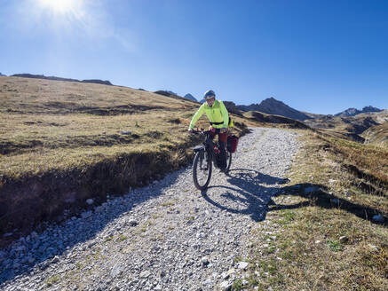 Senior man riding mountain bike on pathway, Vanoise National Park, France - LAF02803