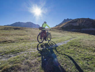 Mann fährt Mountainbike an einem sonnigen Tag unter blauem Himmel im Vanoise-Nationalpark, Frankreich - LAF02813