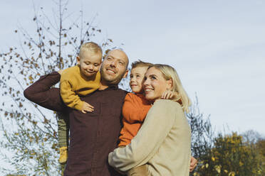 Lächelnde Eltern mit ihren Söhnen unter klarem Himmel im Herbst - AANF00434