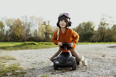 Junge mit Flugbrille spielt mit Bobby Car - AANF00446