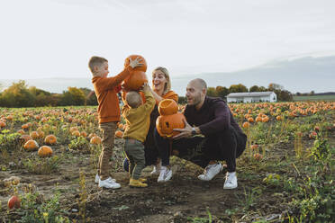 Glückliche Eltern mit Kindern, die Laternen auf einem Feld tragen - AANF00458