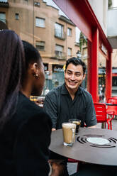 Smiling businessman talking with colleague at sidewalk cafe - GDBF00006