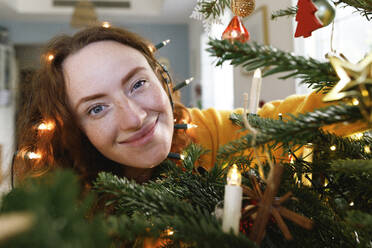 Smiling woman with Christmas lights on head at home - TYF00642