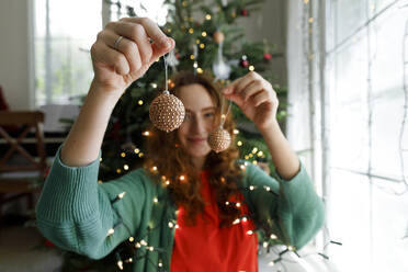 Woman holding Christmas ornaments at home - TYF00670