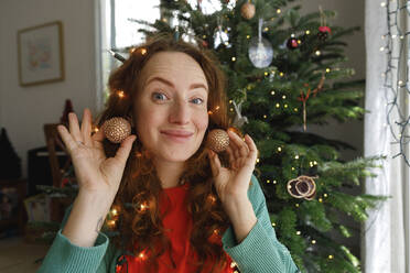 Lächelnde Frau mit Ohrringen vor einem Weihnachtsbaum - TYF00672