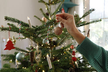 Hand of woman holding Christmas ornament at home - TYF00675