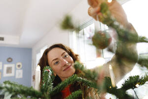 Glückliche Frau hält Weihnachtsschmuck zu Hause - TYF00679