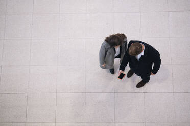 Geschäftskollegen teilen sich ein Smartphone am Bahnhof - AMWF01102