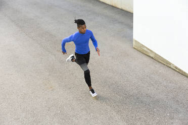 Determined young man running on footpath - JPTF01240