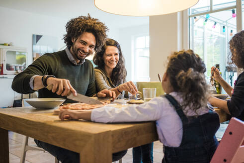 Happy family having food together on dining table at home - MOEF04431