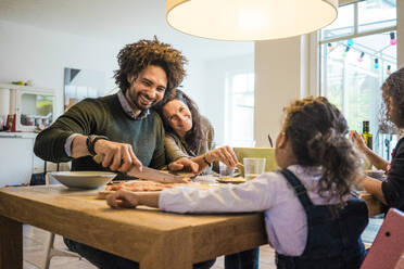 Glückliche Familie beim gemeinsamen Mittagessen am Esstisch zu Hause - MOEF04432