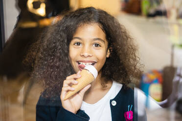 Smiling girl eating ice cream at home - MOEF04434