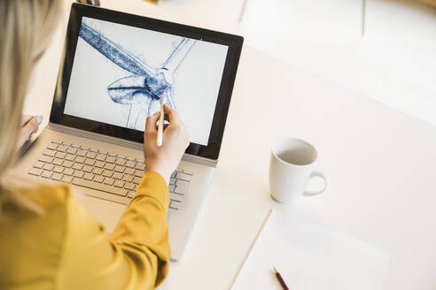 Hand einer jungen Frau, die ein Windrad auf einem Laptop zeichnet - UUF27937