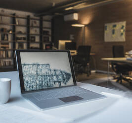 Laptop mit Zeichnung von Sonnenkollektoren auf dem Schreibtisch - UUF27947