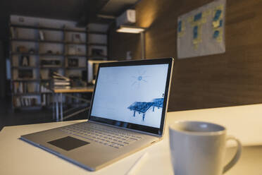 Laptop mit einer Zeichnung von Sonnenkollektoren neben einer Kaffeetasse auf dem Schreibtisch - UUF27962