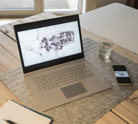 Drawing of wind turbine on laptop screen kept by smart phone at desk - UUF27968