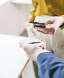 Young businesswoman paying through smart phone on credit card reader - UUF27973