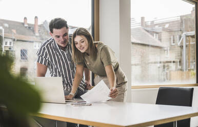 Happy businesswoman discussing over documents at desk - UUF28000