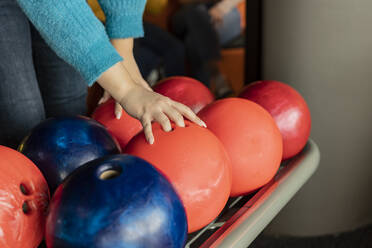 Hand einer Frau hebt Bowlingkugel - JCCMF08759