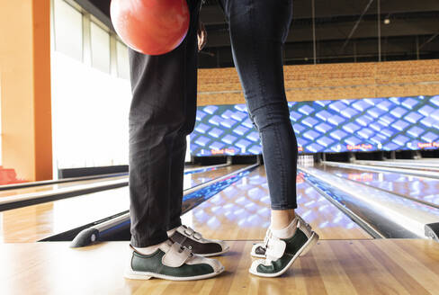 Frau auf Zehenspitzen stehend mit Freund auf der Bowlingbahn - JCCMF08775