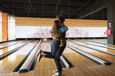 Junges Paar umarmt sich auf der Bowlingbahn - JCCMF08777