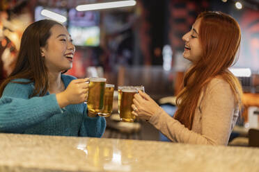 Glückliche junge Freunde mit einem Glas Bier auf der Bowlingbahn - JCCMF08781