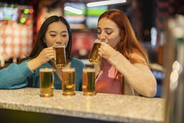 Gemischtrassige Frauen trinken Bier auf der Bowlingbahn - JCCMF08783