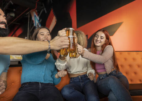 Glückliche multirassische Freunde stoßen auf Bier in einer Bowlingbahn an - JCCMF08803