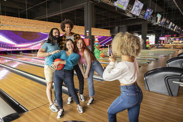 Junge Frau, die in einer Bowlingbahn ein Foto mit ihrem Handy macht - JCCMF08809