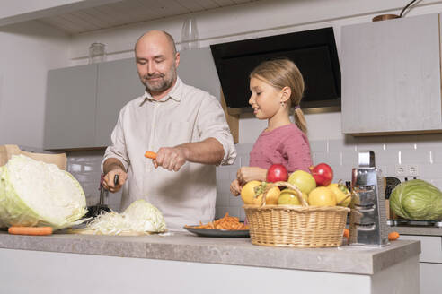 Vater und Tochter bereiten eine gesunde Mahlzeit in der Küche zu Hause zu - KMKF01917