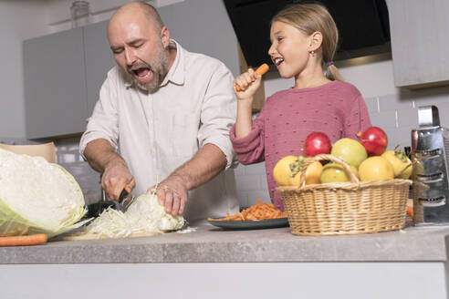 Vater und Tochter bereiten eine gesunde Mahlzeit zu und haben Spaß in der Küche zu Hause - KMKF01918