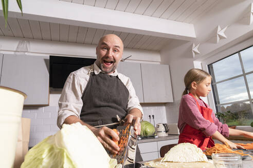 Glücklicher Vater und Tochter bei der Zubereitung einer gesunden Mahlzeit in der Küche zu Hause - KMKF01919