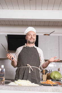 Porträt eines Mannes in Kochkleidung in der Küche zu Hause - KMKF01920