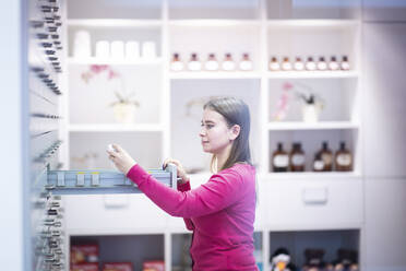 Junge Apothekerin bei der Prüfung von Medikamenten in einer Apotheke - NJAF00178