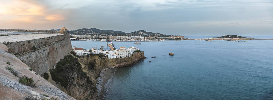 Spanien, Balearische Inseln, Ibiza, Panoramablick auf den Rand der Küstenstadt in der Abenddämmerung - JAQF01154