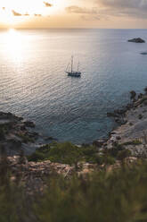 Spanien, Balearen, Segelboot schwimmt in der Nähe von Ufer bei Sonnenuntergang - JAQF01160