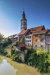 Slowenien, Oberkrain, Skofja Loka, Häuser am Flussufer mit Glockenturm der Kirche St. Jakob im Hintergrund - ABOF00859